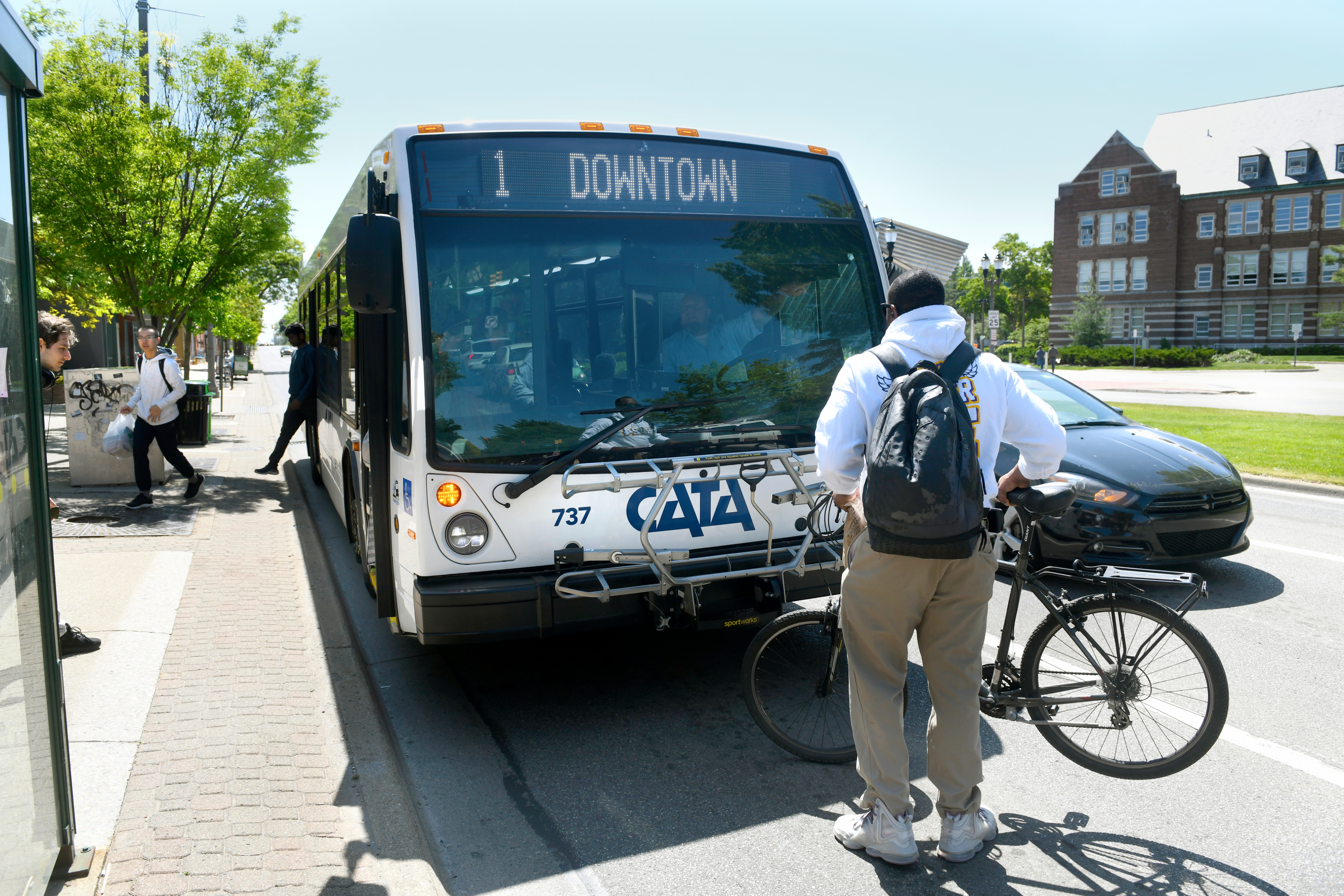a man standing infront of cata transit with bicycle