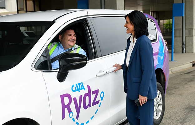A woman talking with the driver of a CATA Rydz Vehicle