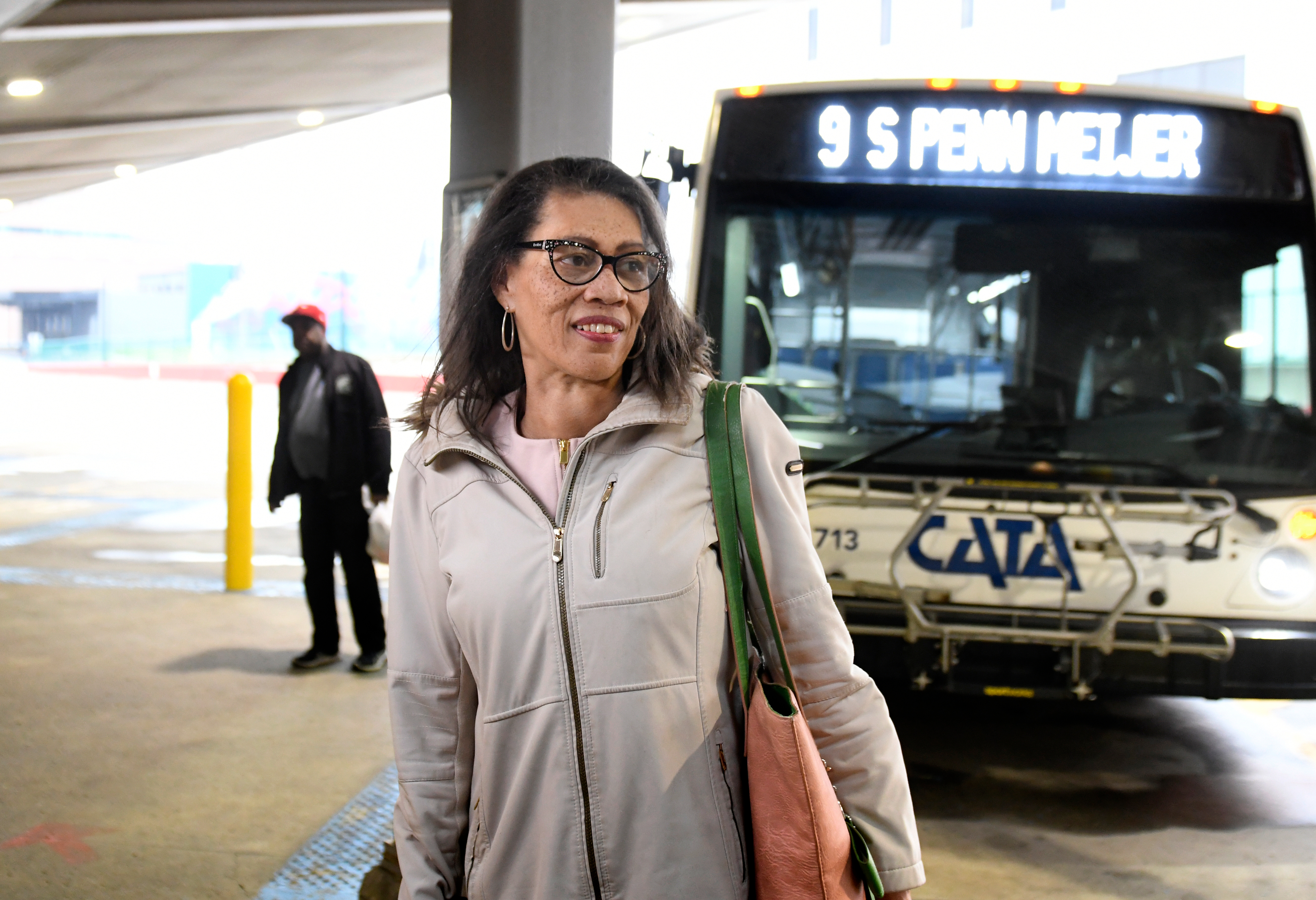 Woman with glasses standing in front of a city bus