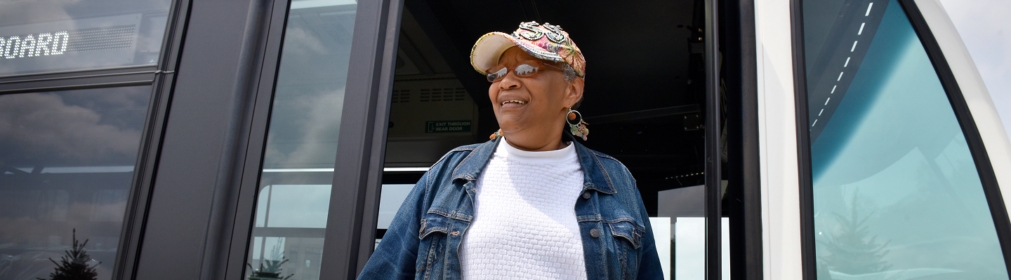 Banner showing older woman in a denim jacket standing in a bus doorway