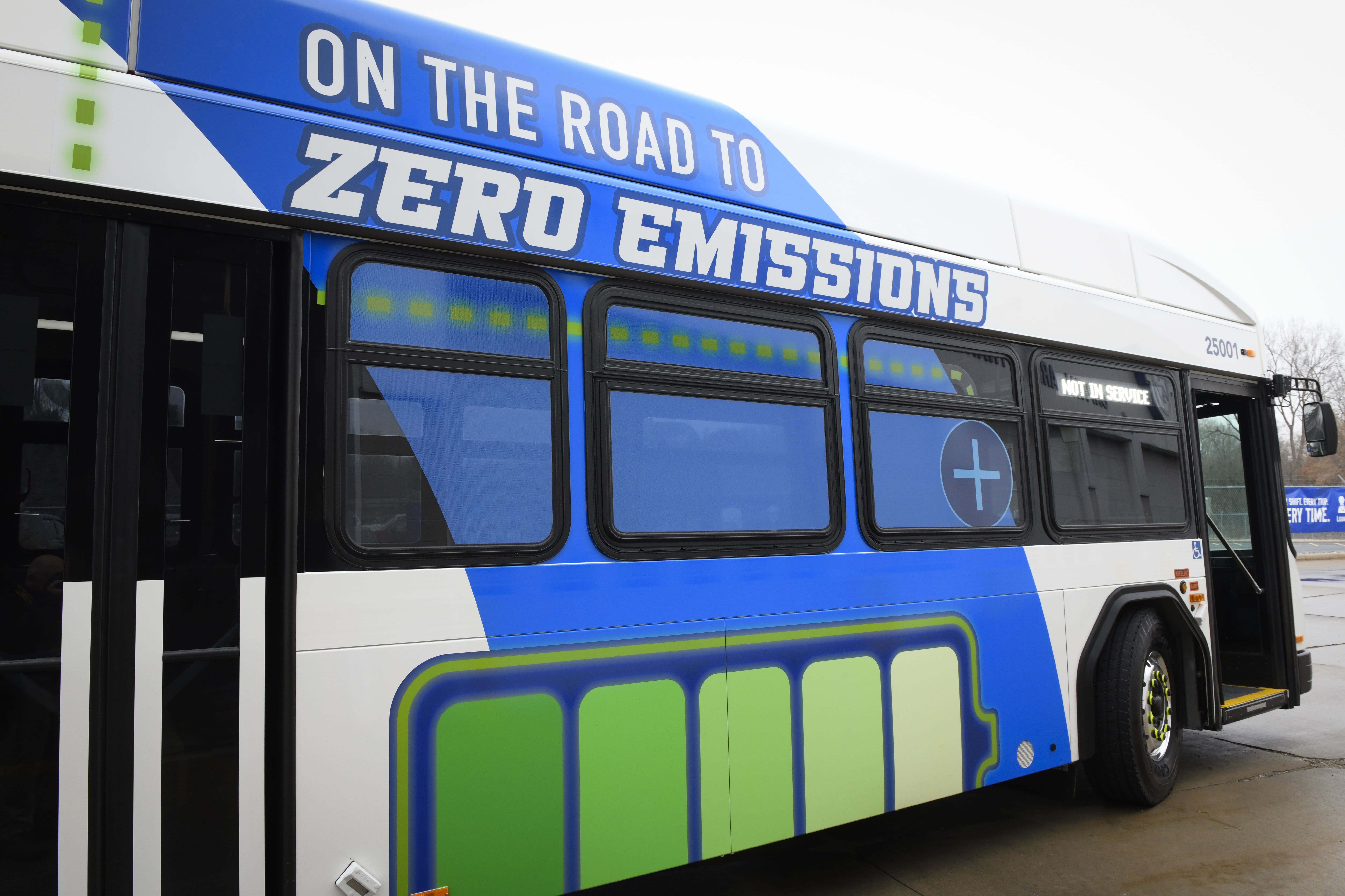 Close-up view of CATA's electric bus showing the wrap saying On the Road to Zero emissions with a graphic of a battery