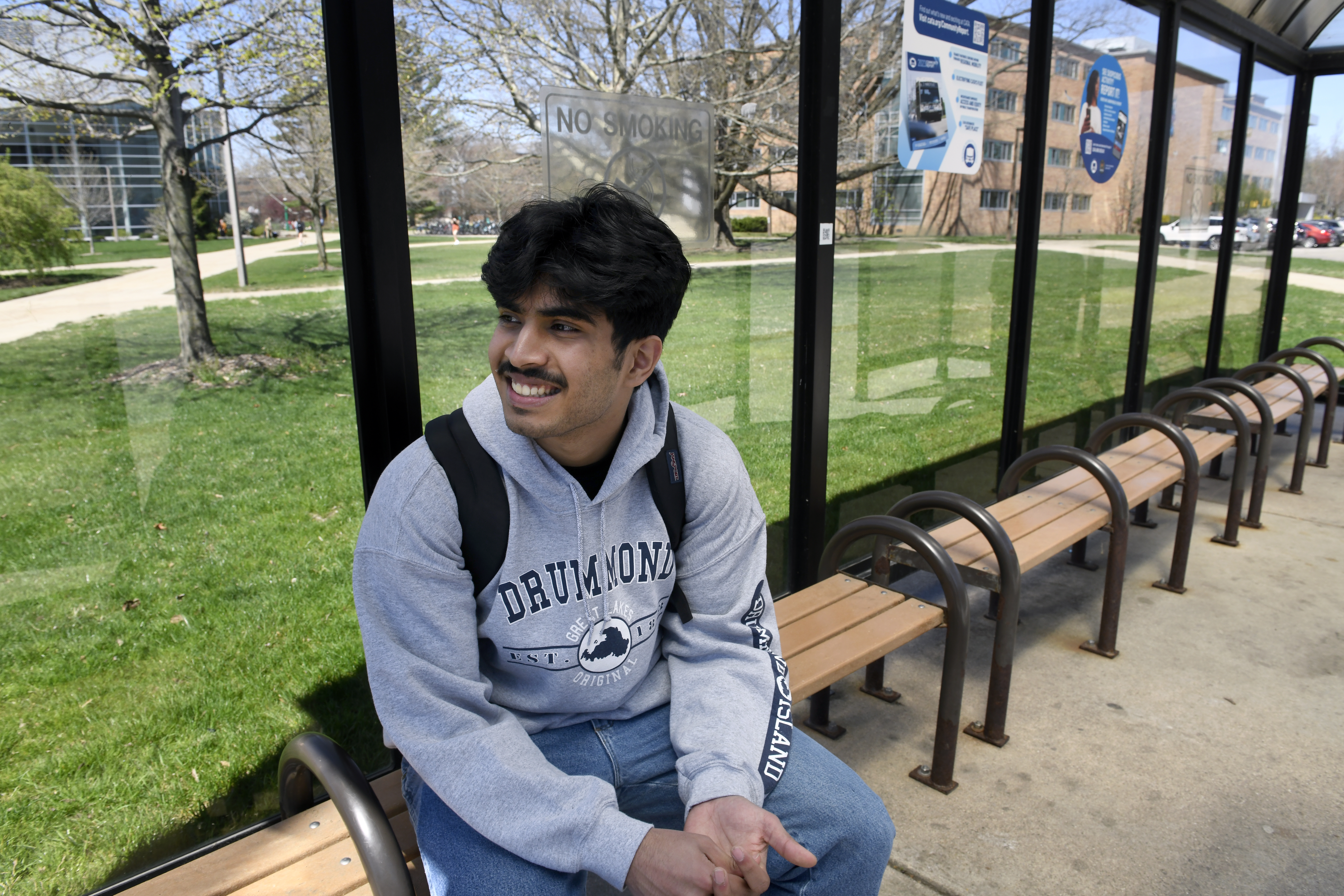 Photo of student sitting at a bus stop