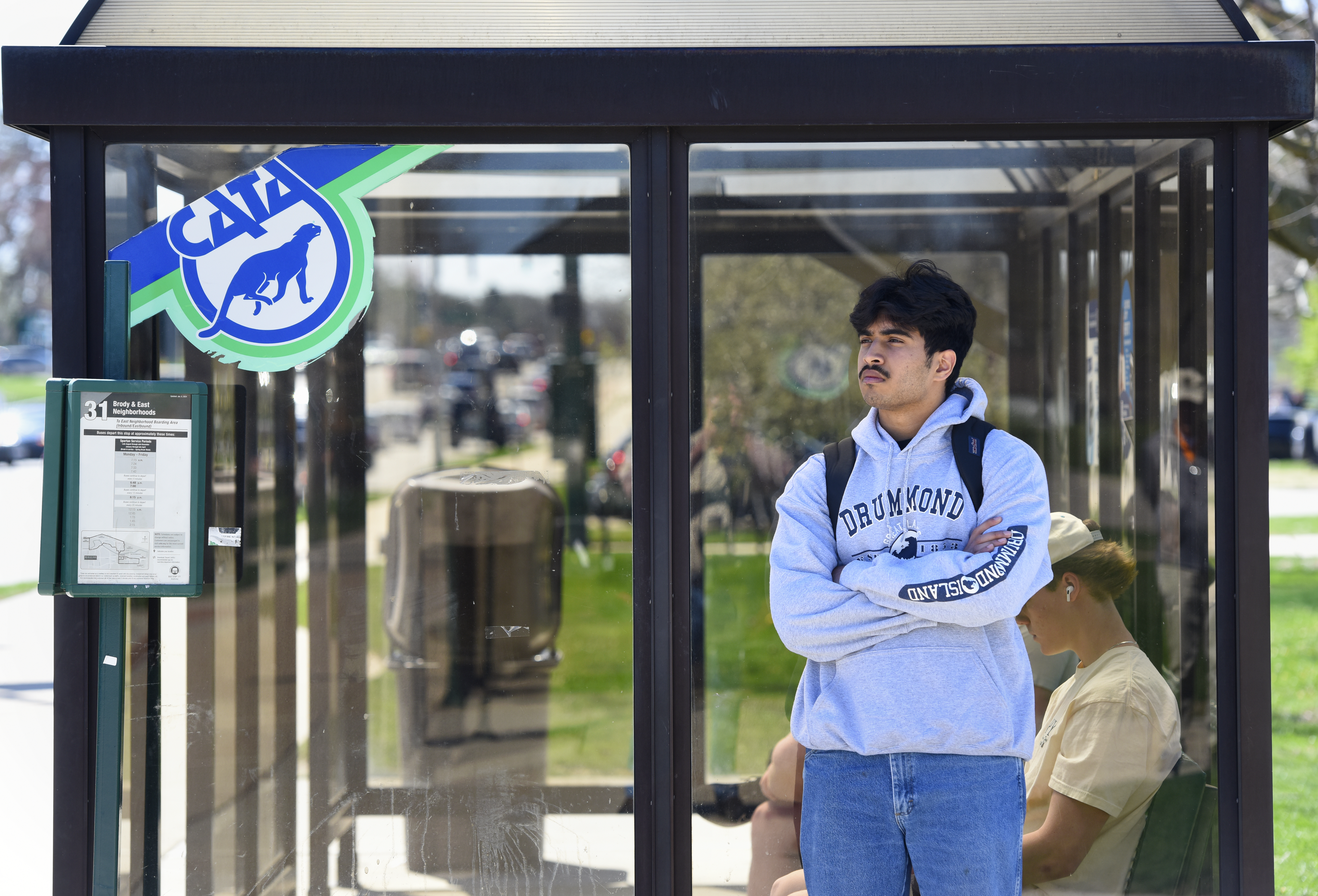 MSU student standing at a CATA bus stop