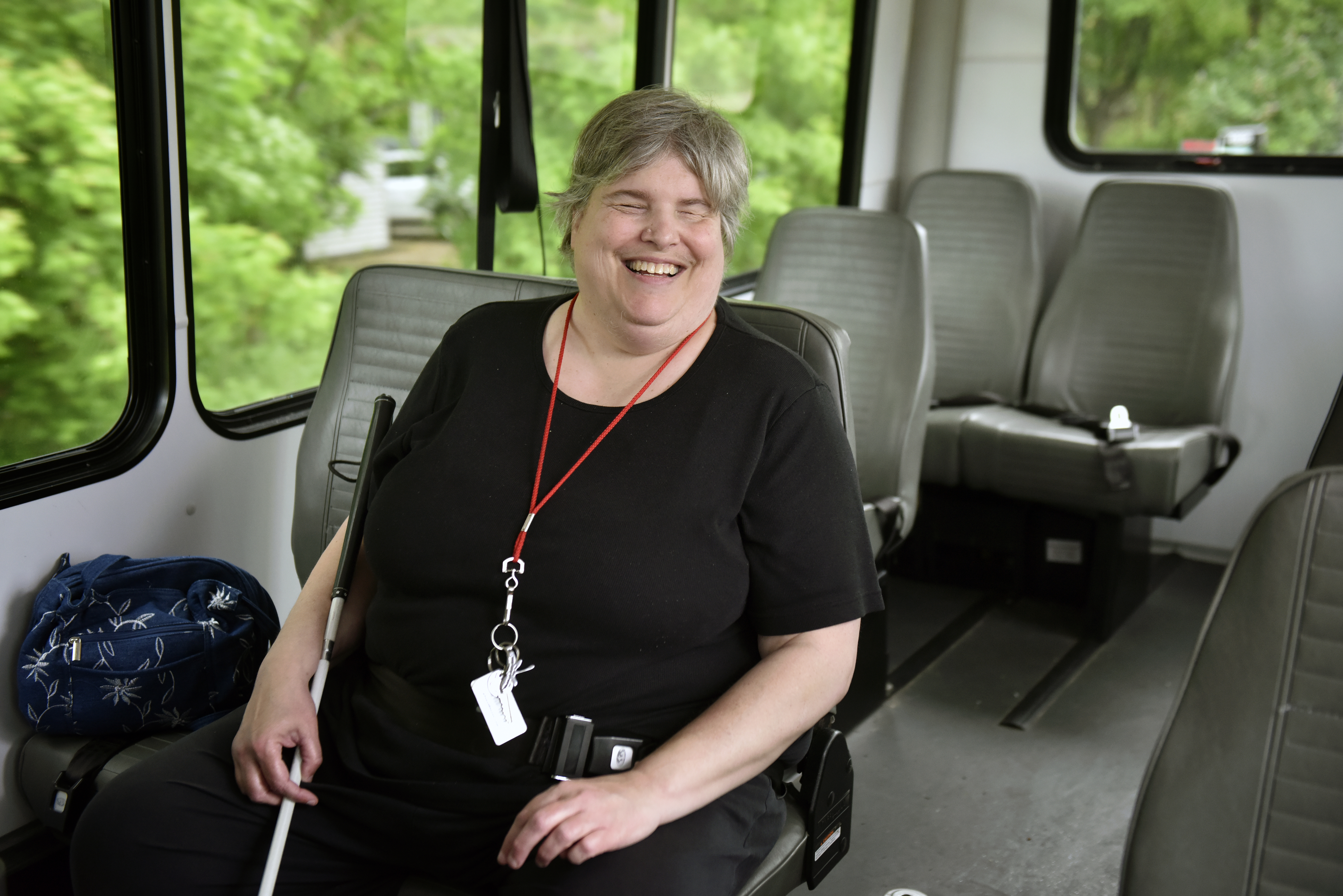 CATA rider sitting onboard a vehicle with a white mobility cane beside them
