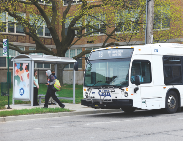 CATA bus at bus stop with a shelter and people walking by