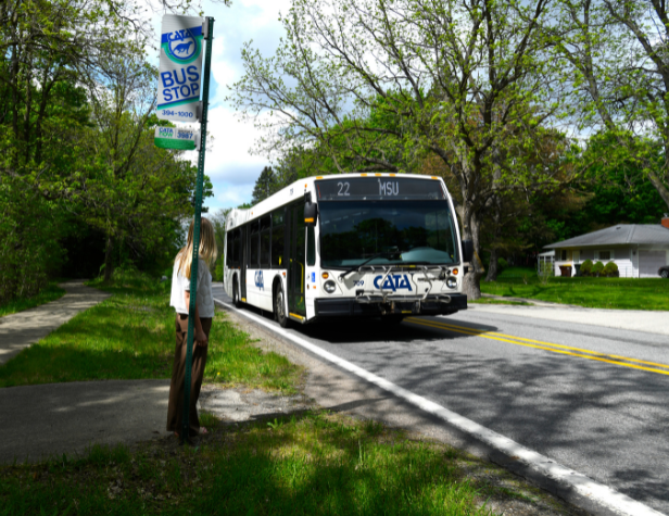 A woman waiting for a bus heading towards MSU