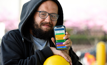 A man looking directly at the camera, holding his phone with Transit app open