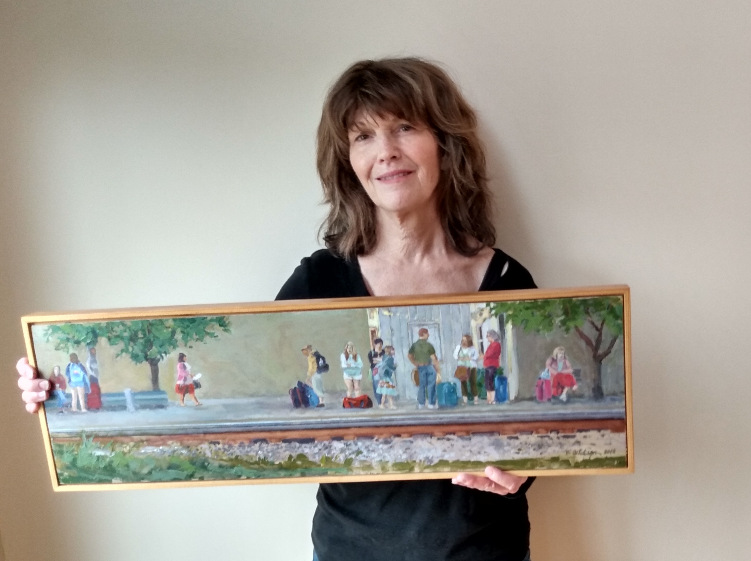 Aitchenson stands holding her panoramic art piece of the people waiting for the train