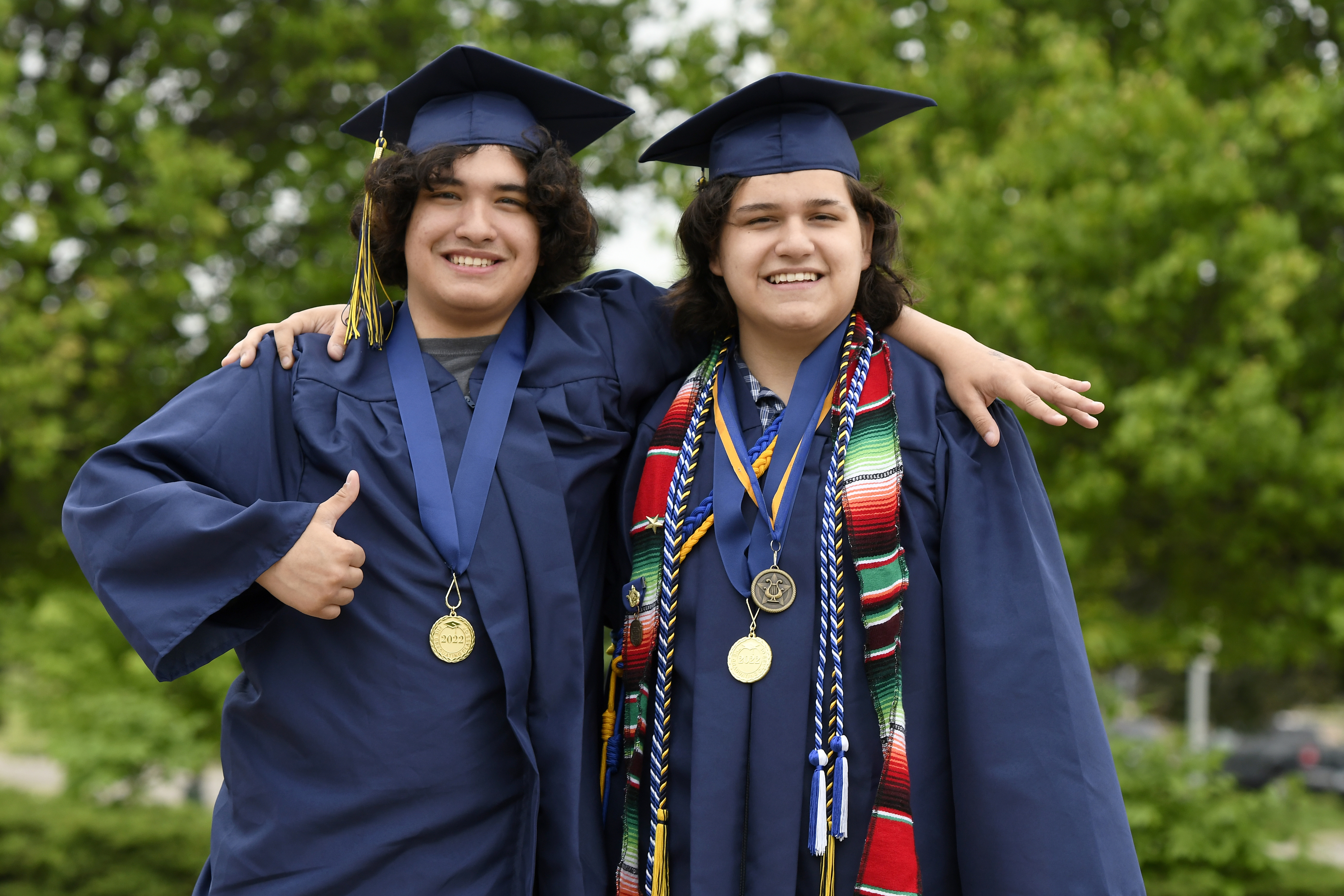 Deric and Eric smile in their graduation caps and gowns in front of Eastern high school