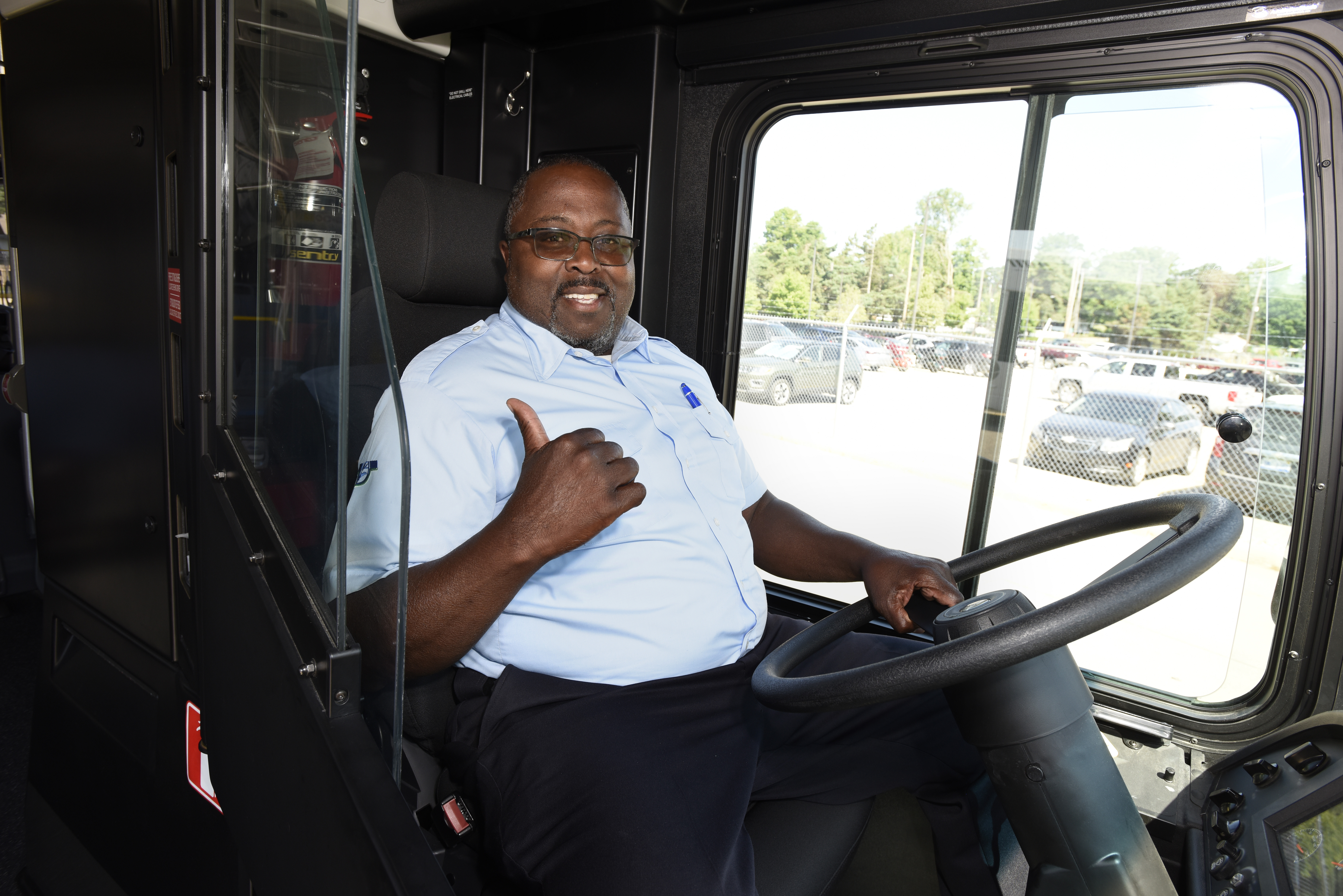 Smiling man sits in the driver seat of the electric bus
