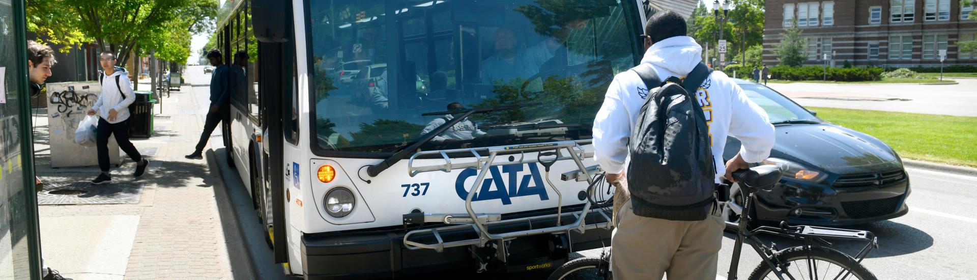 a man standing infront of cata transit with bicycle