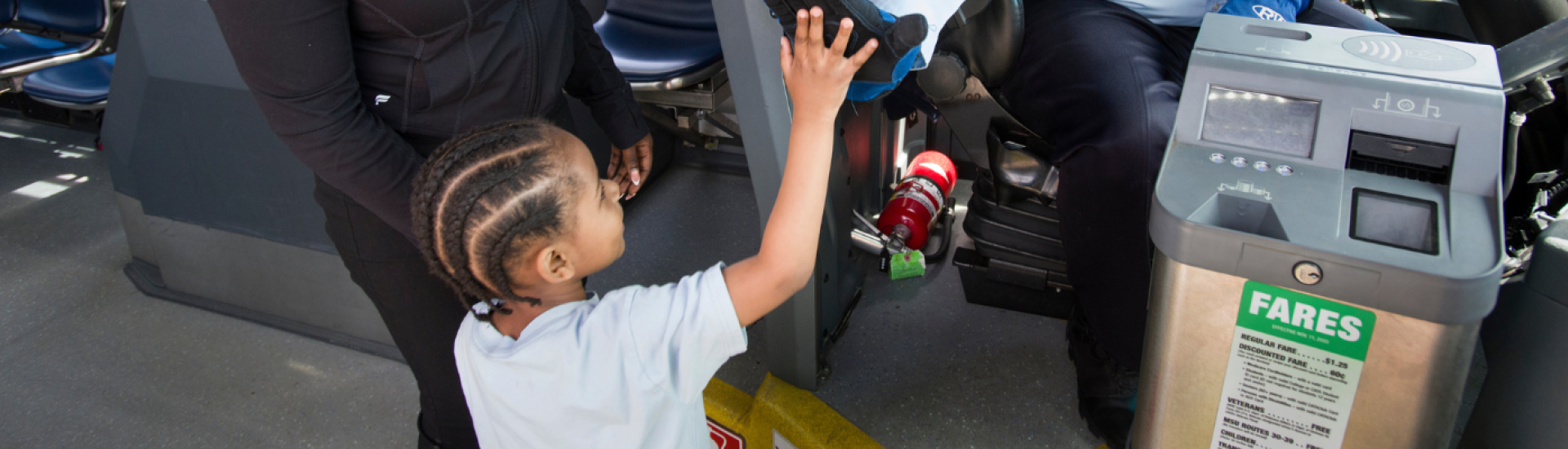 A child high-fiving a driver next to a CATA farebox