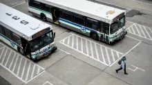 “Aerial view of two white CATA buses parked in designated stalls while a pedestrian walks nearby on the pavement.